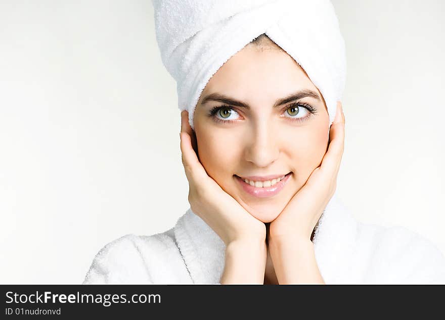 Portrait of a pretty girl wrapped into the white towel and wearing a white dressing gown