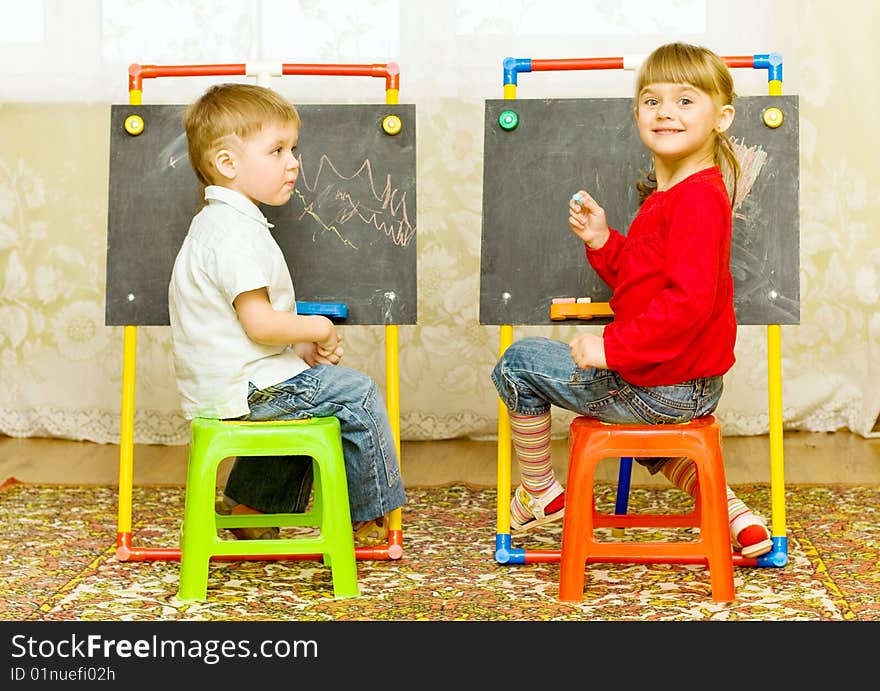 Girl and boy drawing on the blackboard with chalk