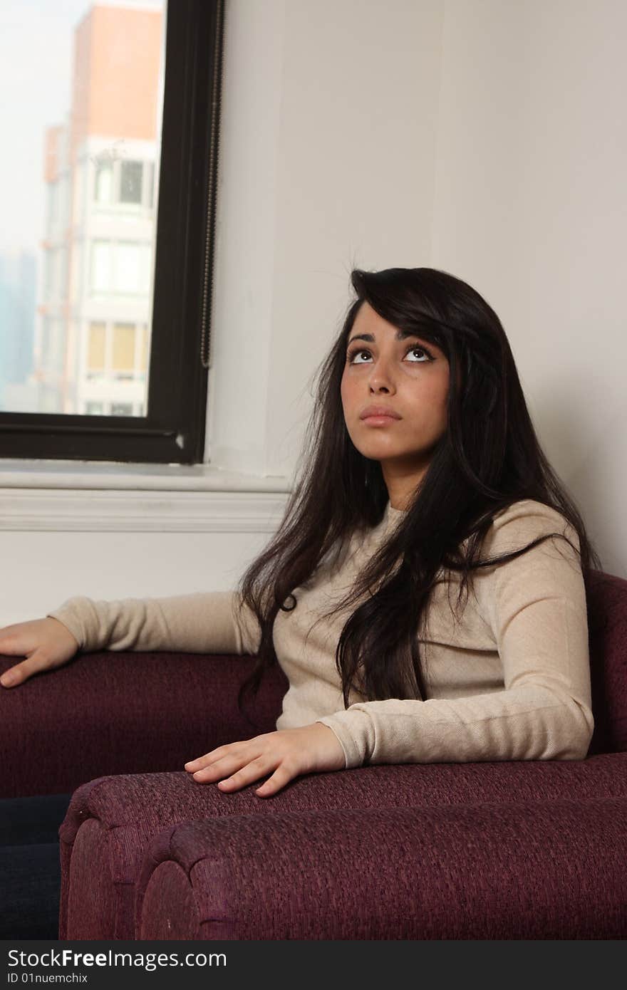 Young female sitting in arm chair, scared, looking up. Young female sitting in arm chair, scared, looking up