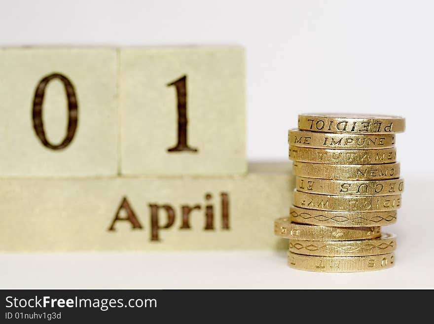 A close up photo of English one pound coins with the first of April showing in the background. A close up photo of English one pound coins with the first of April showing in the background