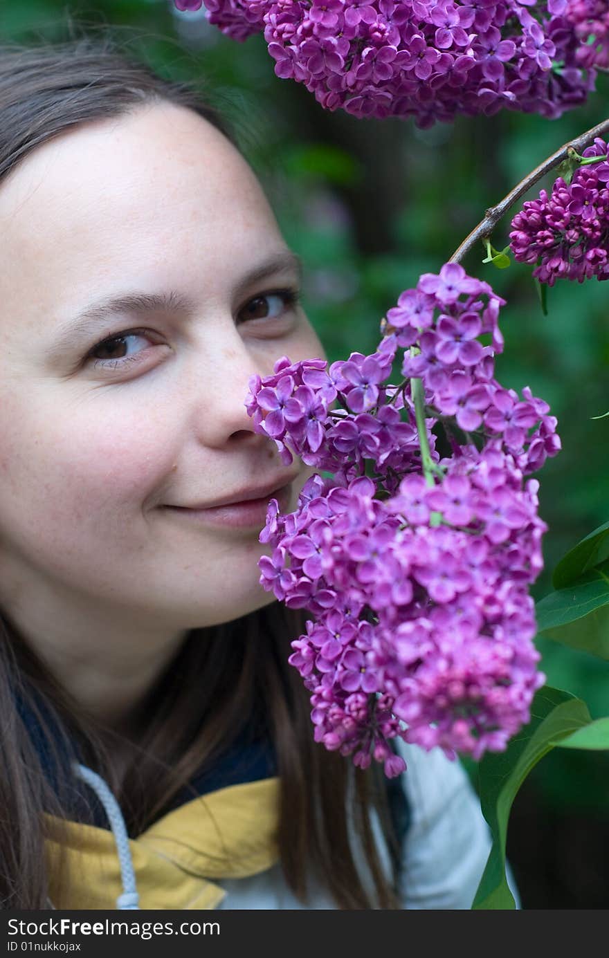 Young woman smelling the lilac flower and smiling. Young woman smelling the lilac flower and smiling