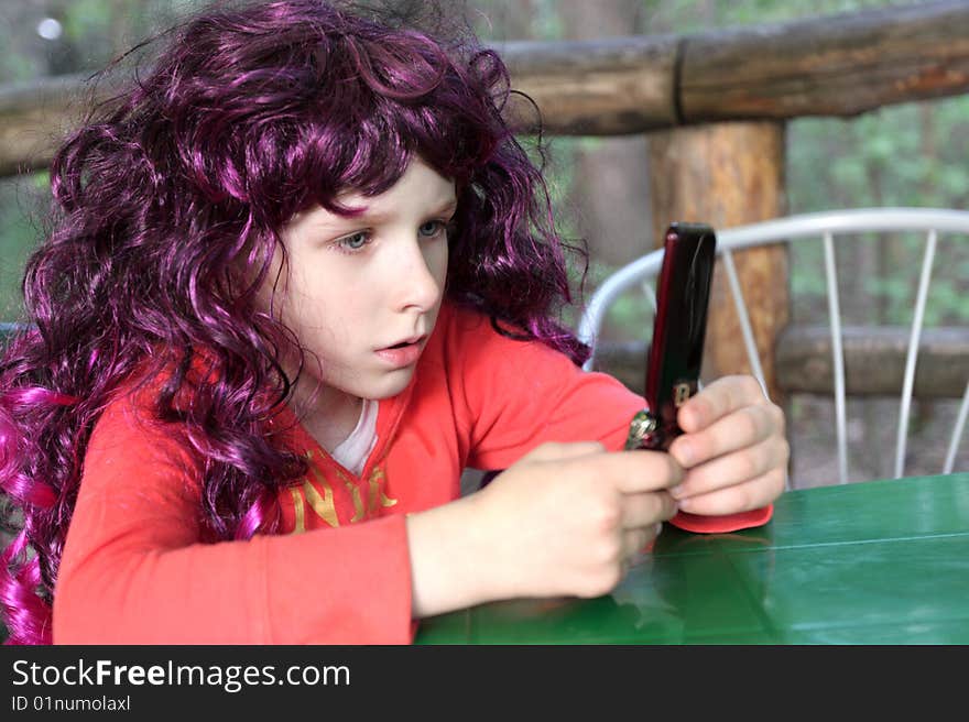 The girl plays by a mobile phone. The girl plays by a mobile phone