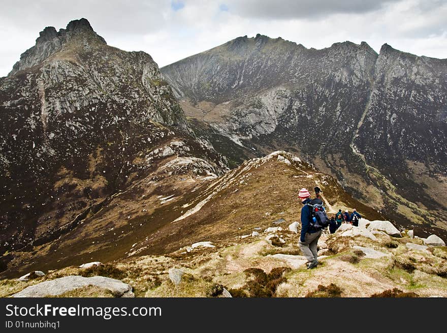 Woman walker with trekking poles on path in the mountains. Woman walker with trekking poles on path in the mountains