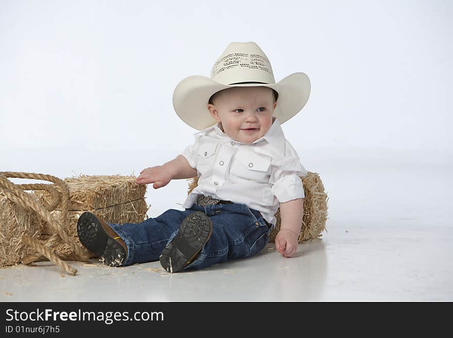 Little boy on white with cowboy hat on white background with hay bales and rope. Little boy on white with cowboy hat on white background with hay bales and rope