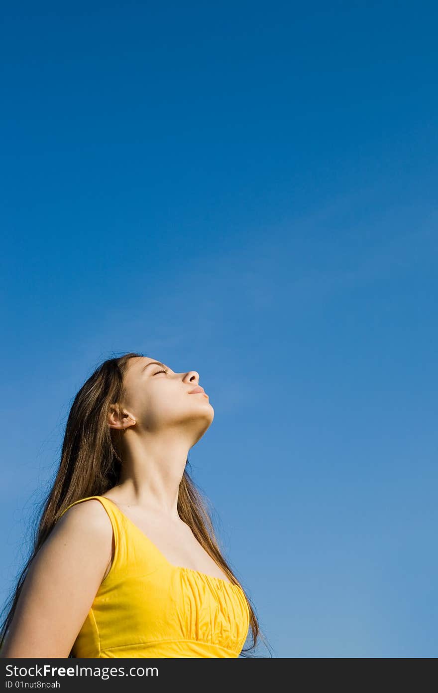 A young girl in yellow listen the silence on the sky fon. A young girl in yellow listen the silence on the sky fon