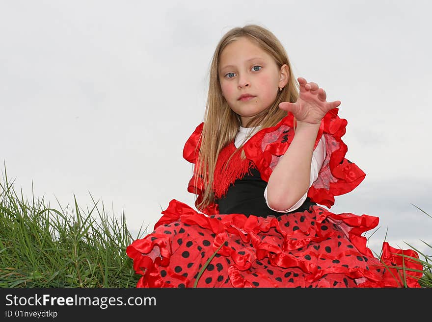 Girl in the red dress is sitting on the grass. Girl in the red dress is sitting on the grass