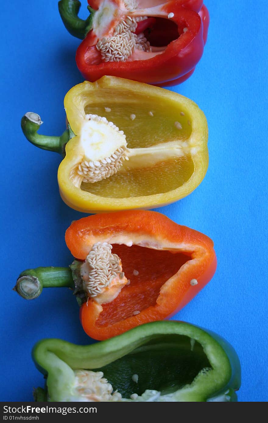 Peppers green Yellow Orange and Rd lined up in a row cut in half with seeds showing. Peppers green Yellow Orange and Rd lined up in a row cut in half with seeds showing