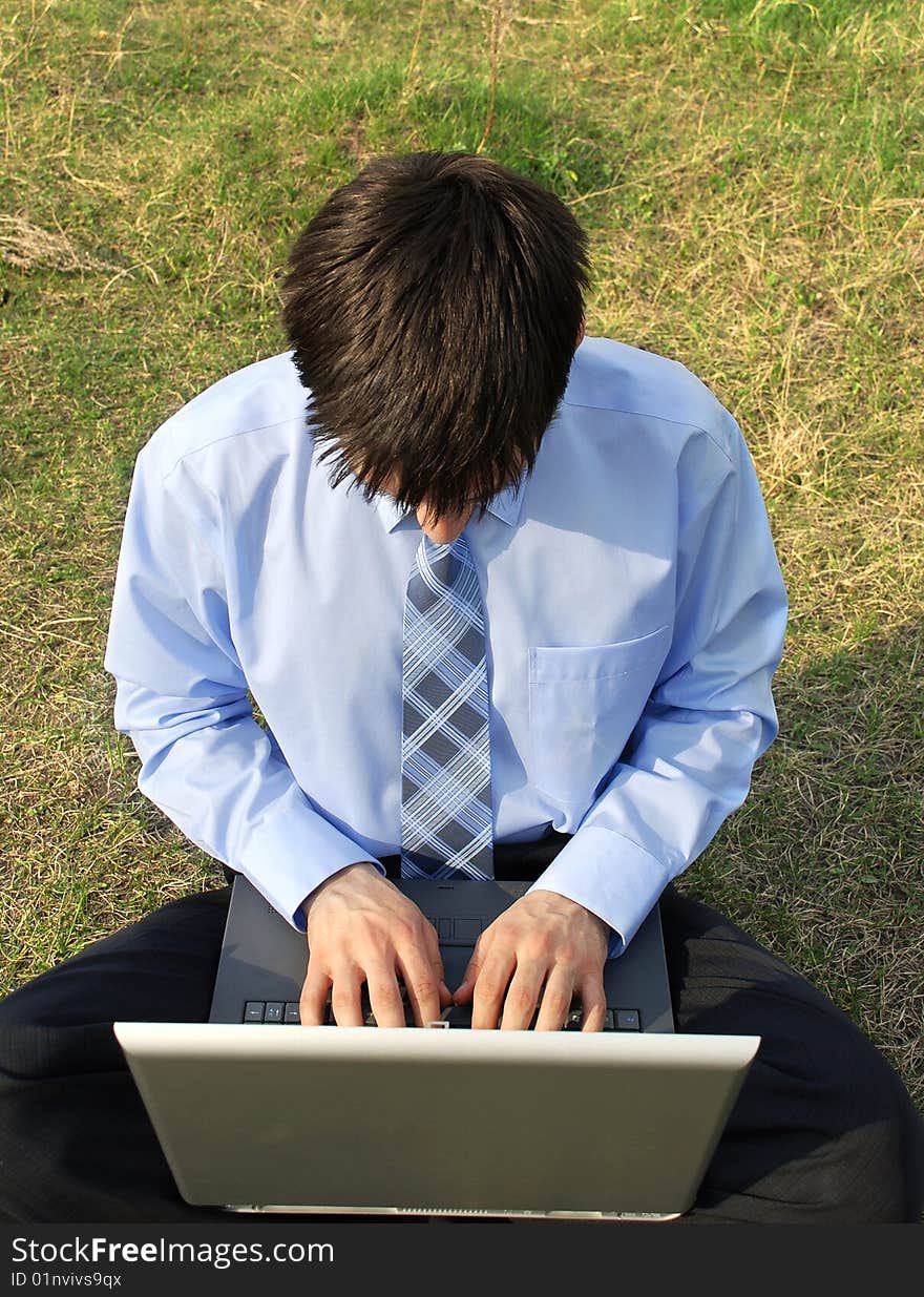 Businessman sitting on the grass with laptop, very concentrated, working hard