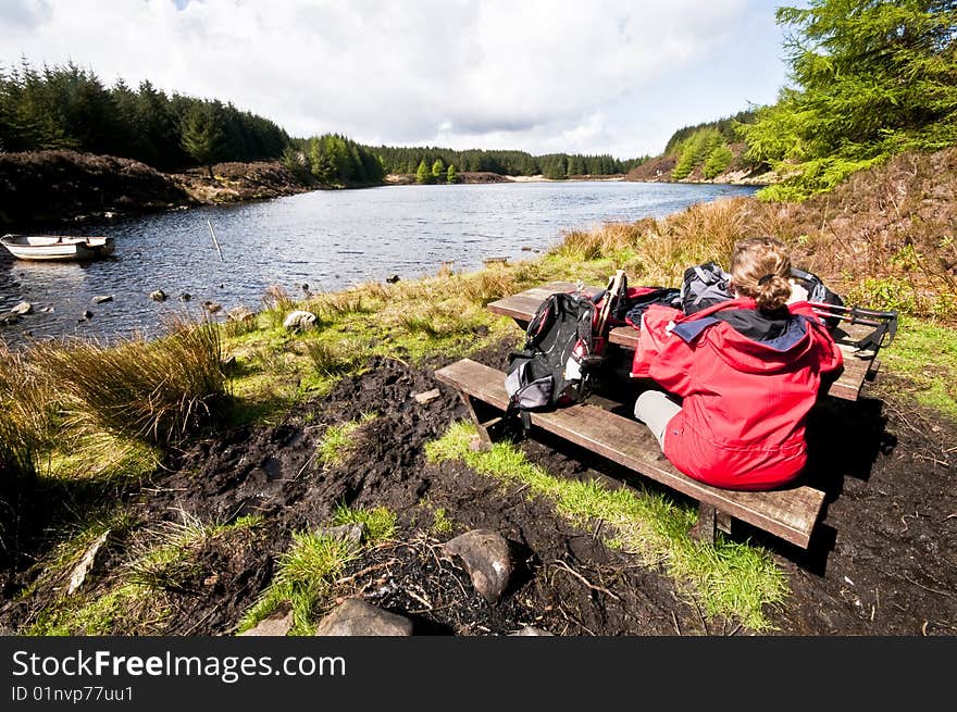 Woman relaxing by lake in remote loch in scotland