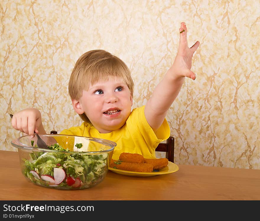 The little boy eats fresh salad. The little boy eats fresh salad
