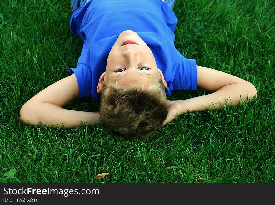 Cute blond boy on the green grass