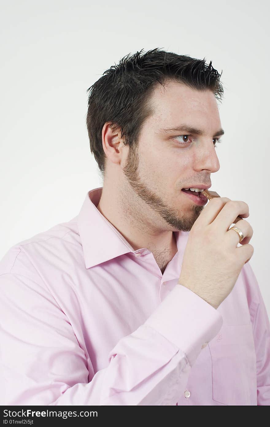 Young, handsome man, eating a chocolate, looking sideways. Young, handsome man, eating a chocolate, looking sideways