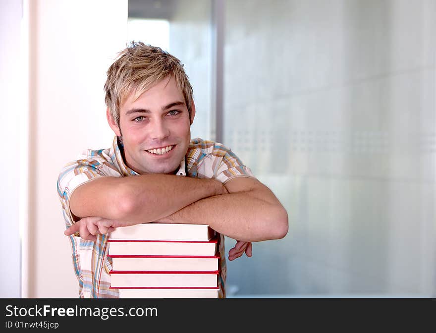 Portrait of male student leaning on books.