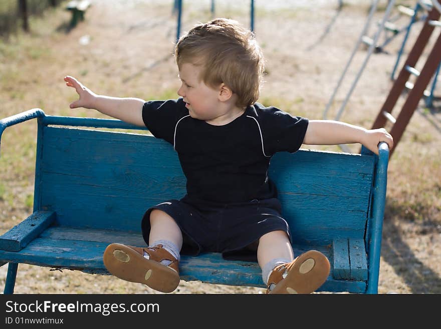 The child sits on a bench blue. The child sits on a bench blue.