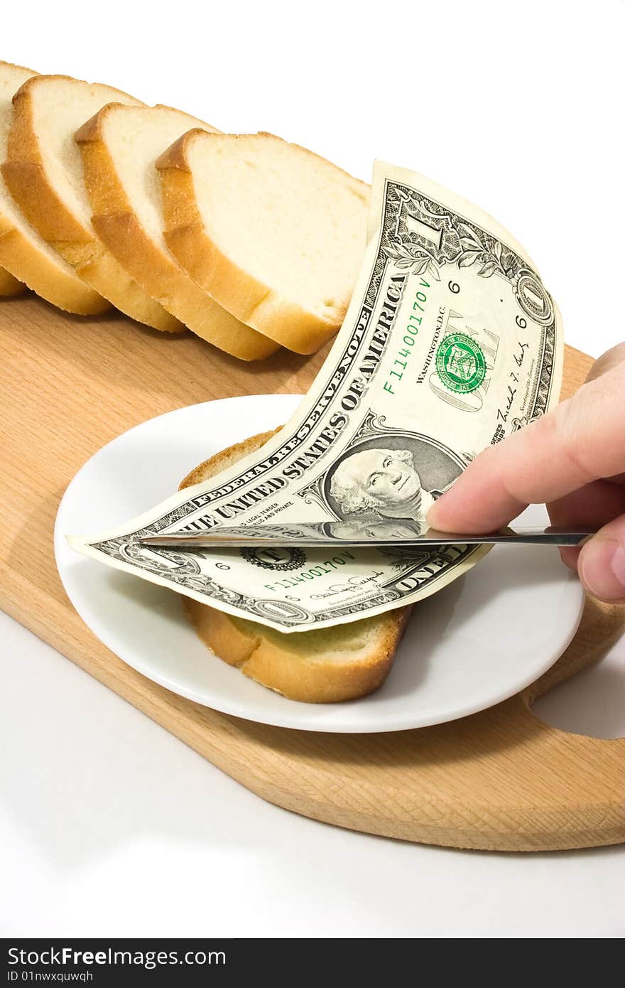 Hand spreads bread with one-dollar banknote on small plate on chopping board. Hand spreads bread with one-dollar banknote on small plate on chopping board