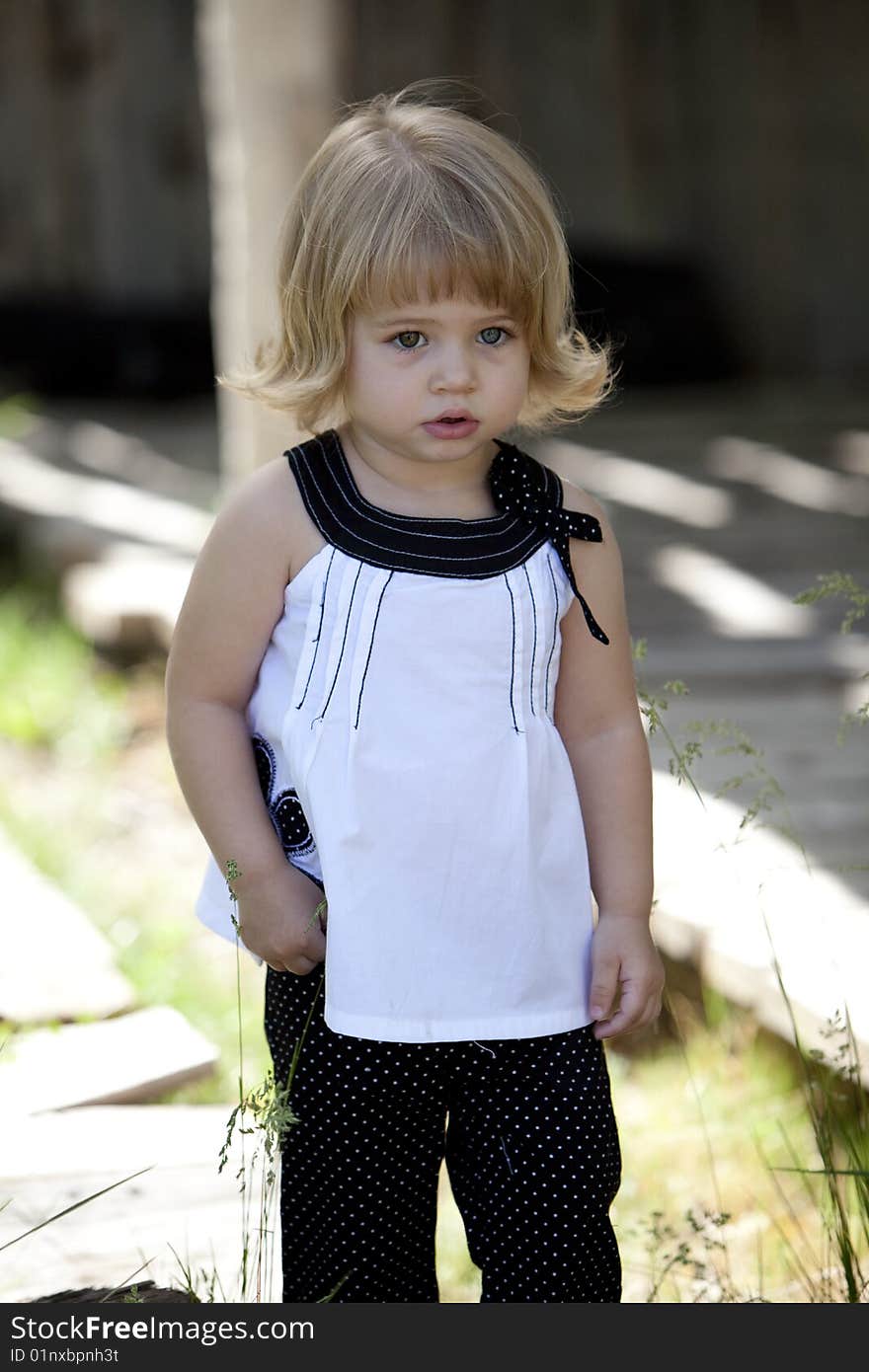 Little girl standing next to barn in white. Little girl standing next to barn in white