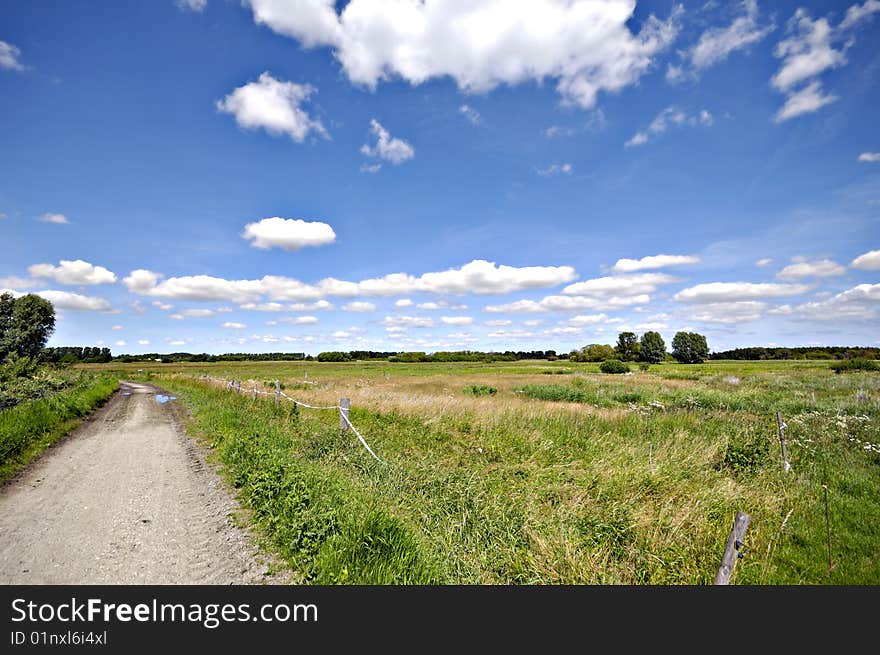 Path and green landscape with blue and cloudy sky. Path and green landscape with blue and cloudy sky