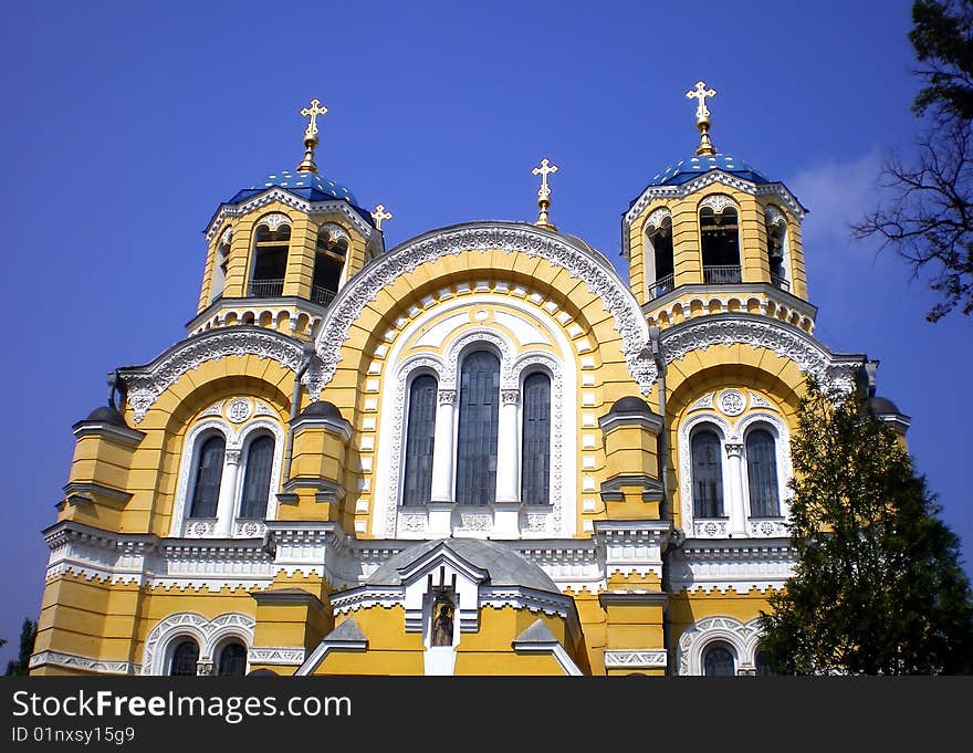 Domes of cathedral with a shining gold cross in framing of dry branches and cypress. Domes of cathedral with a shining gold cross in framing of dry branches and cypress