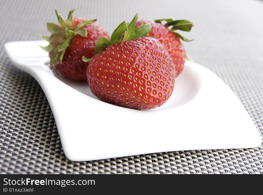 Three ripe strawberries on a white plate. Three ripe strawberries on a white plate