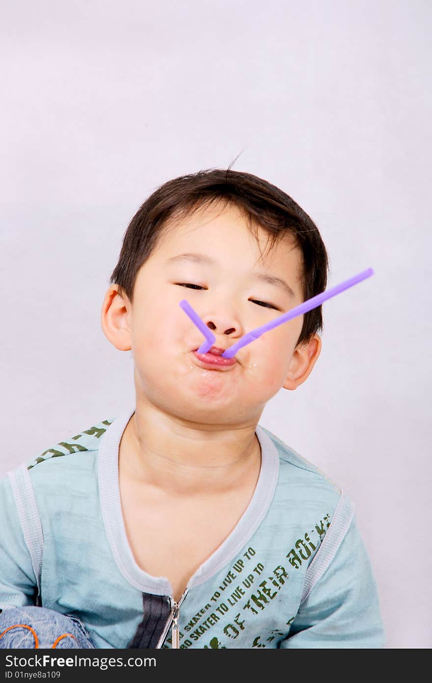 A picture of a little chinese boy playing with a purple straw. A picture of a little chinese boy playing with a purple straw