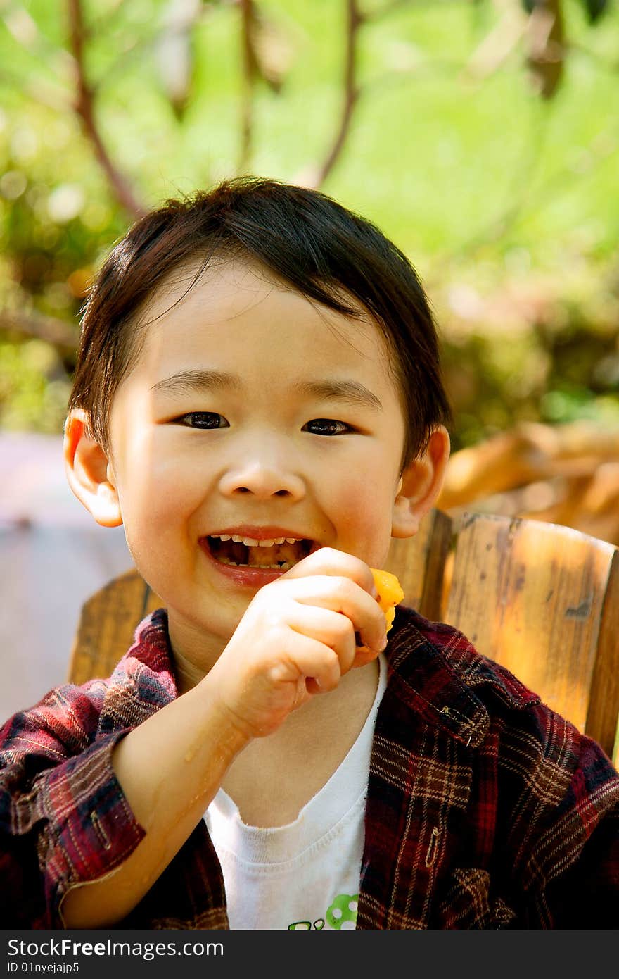 A picture of a little chinese boy eating loquat and enjoying it greatly