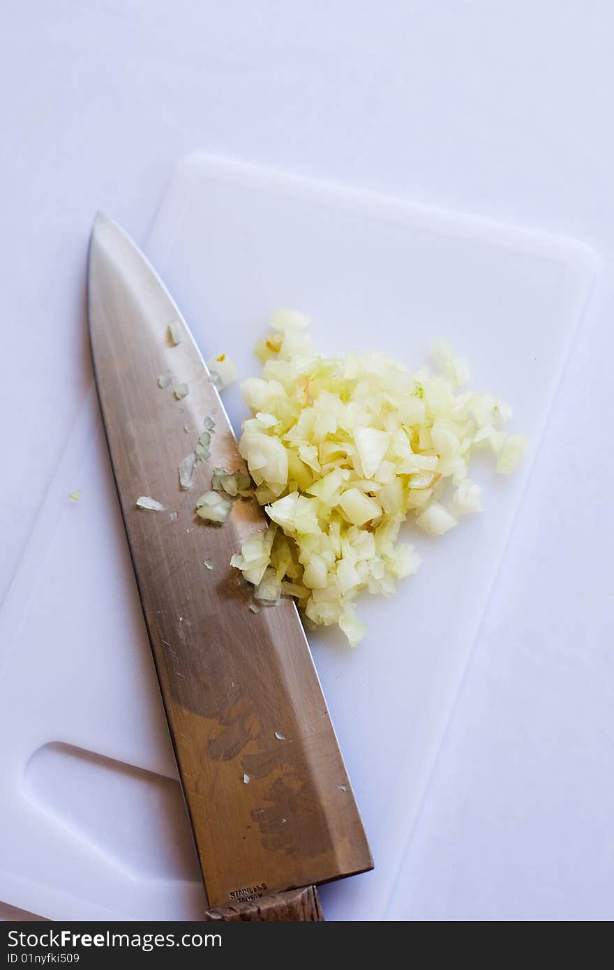 White onion minced by a chef's knife on a cutting board. White onion minced by a chef's knife on a cutting board