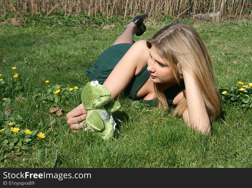 Girl with a toy frog lying on grass