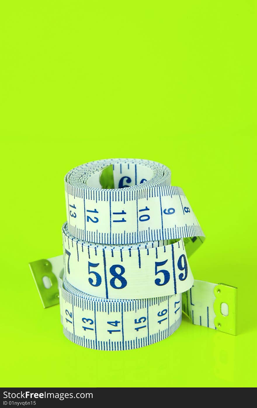 A measuring tape isolated against a lime green background. A measuring tape isolated against a lime green background