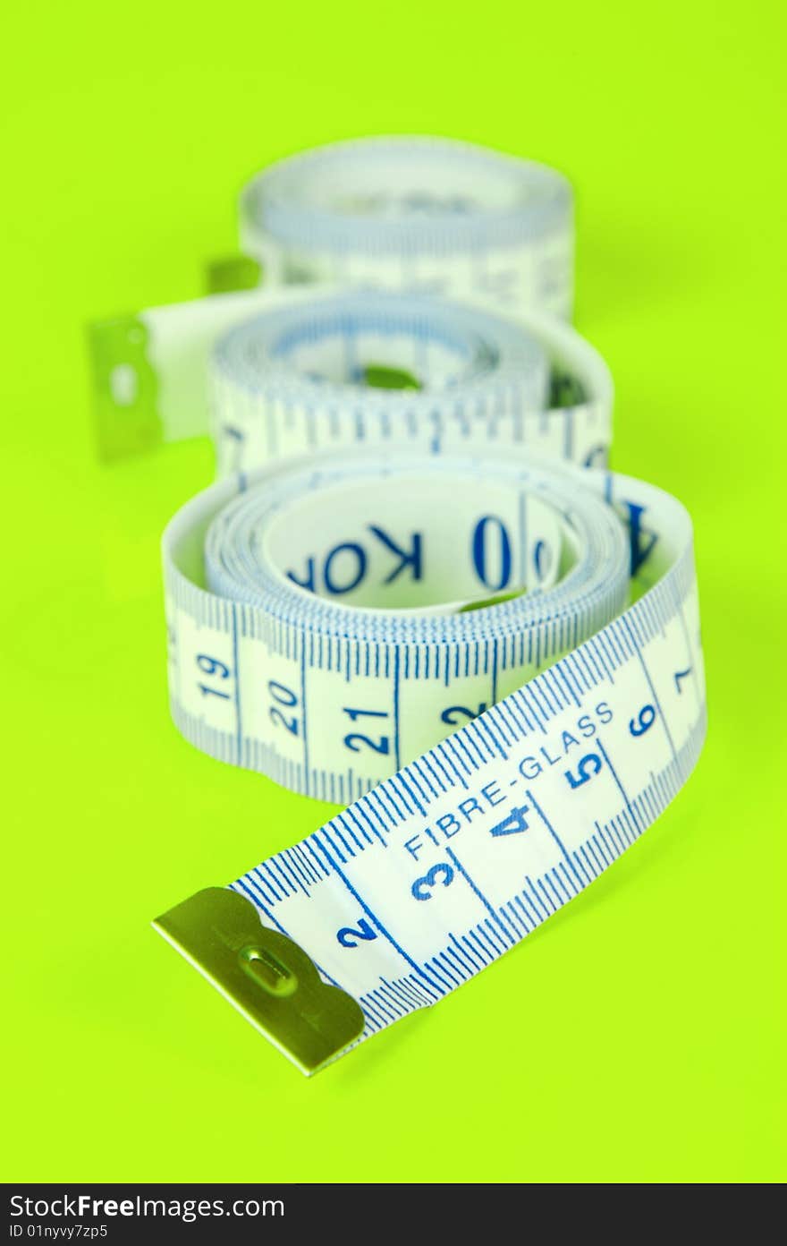 A measuring tape isolated against a lime green background. A measuring tape isolated against a lime green background