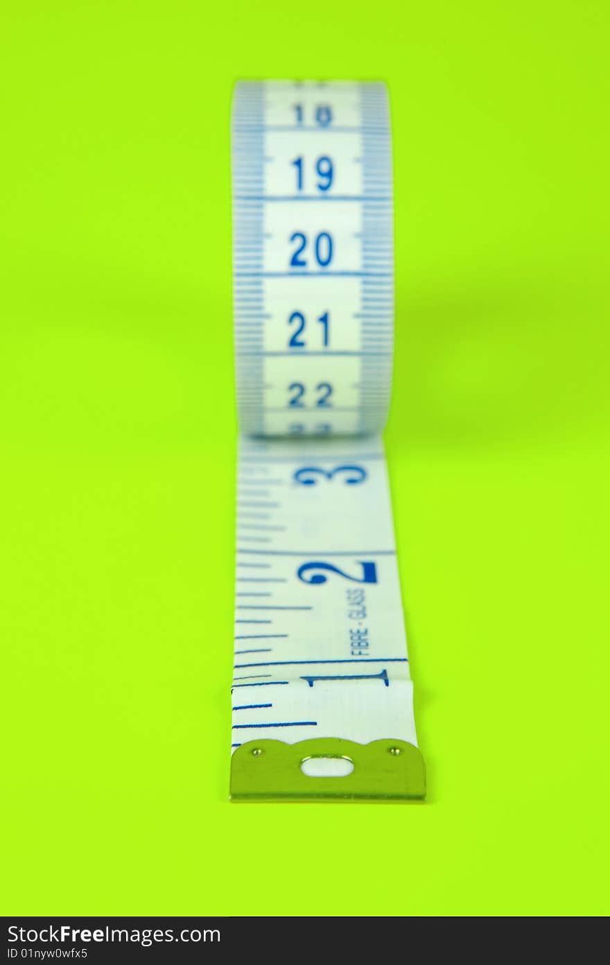 A measuring tape isolated against a lime green background. A measuring tape isolated against a lime green background