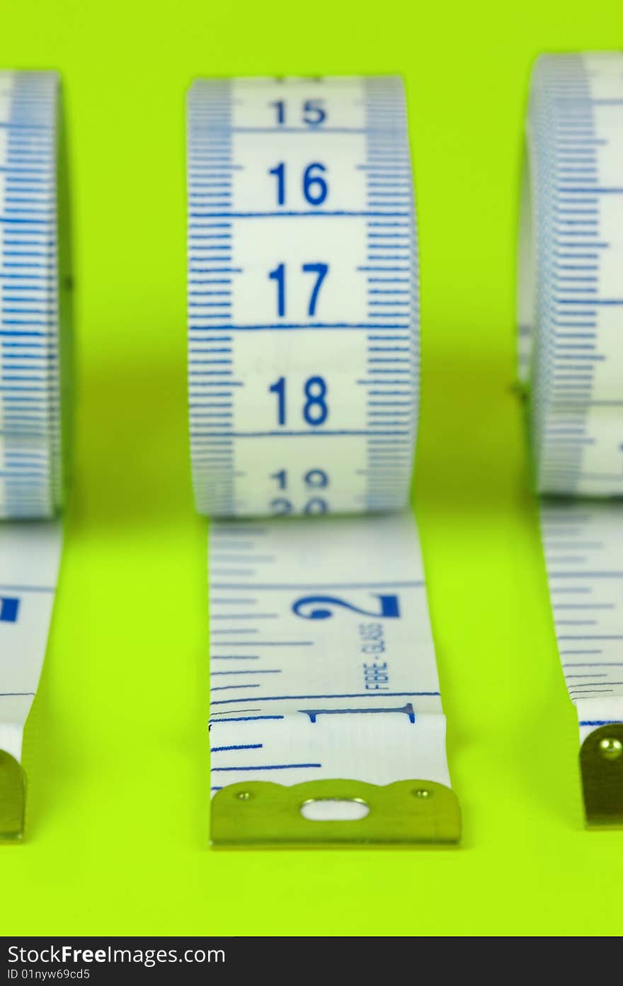 A measuring tape isolated against a lime green background. A measuring tape isolated against a lime green background