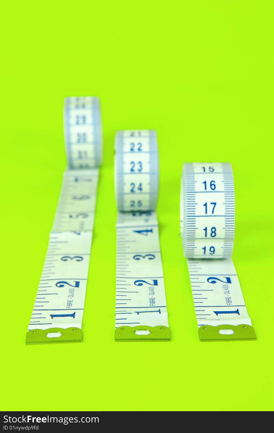 A measuring tape isolated against a lime green background. A measuring tape isolated against a lime green background