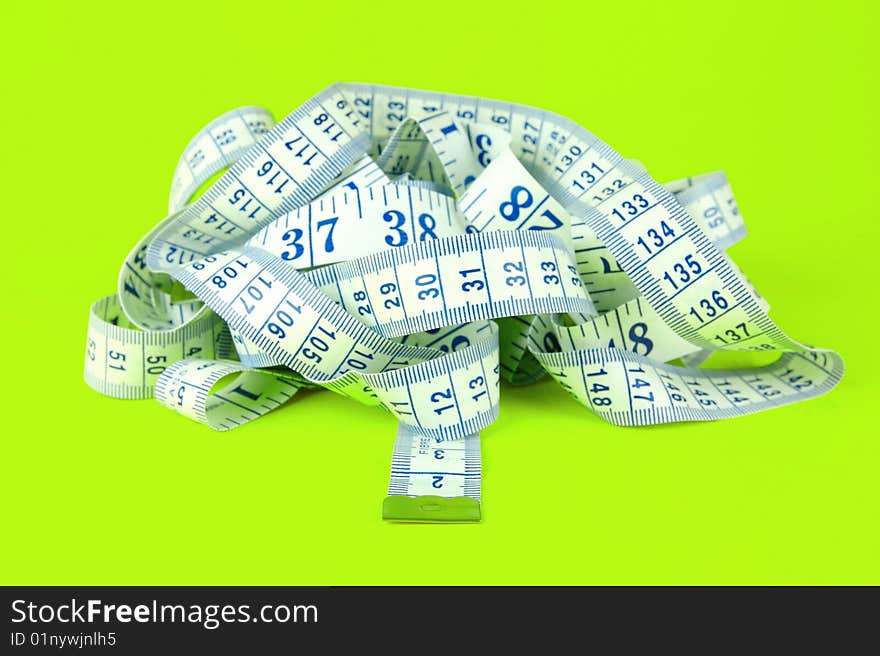 A measuring tape isolated against a lime green background. A measuring tape isolated against a lime green background