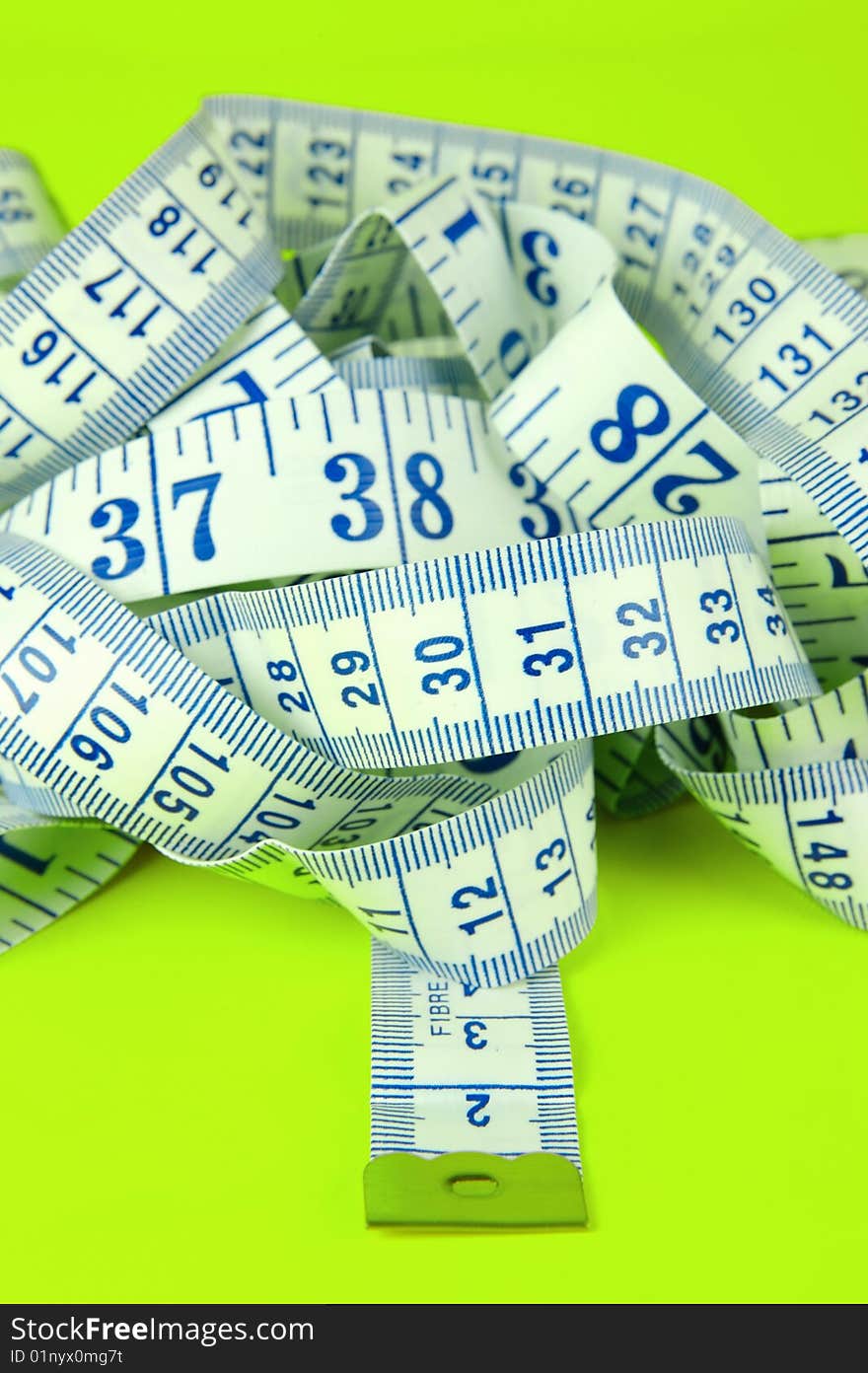 A measuring tape isolated against a lime green background. A measuring tape isolated against a lime green background