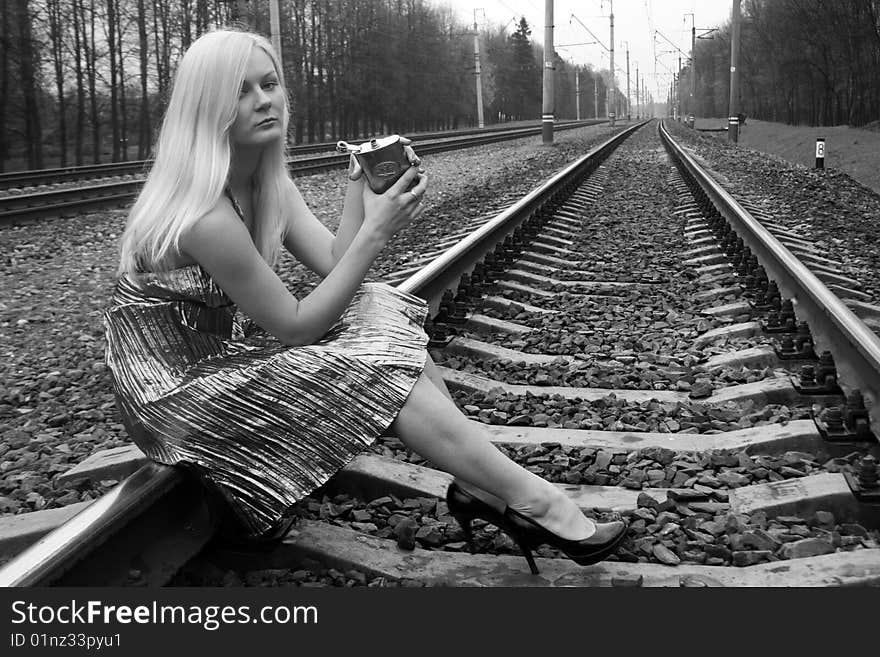 Girl with a flask sitting near railroad