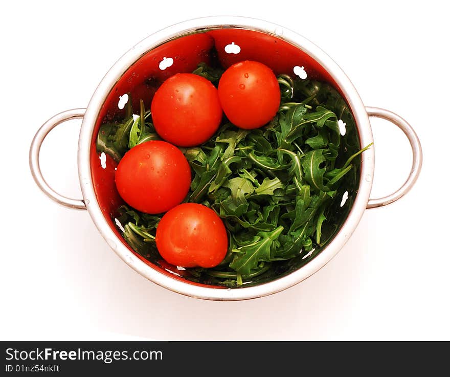 Arugula and tomatoes in stainless steel stainer