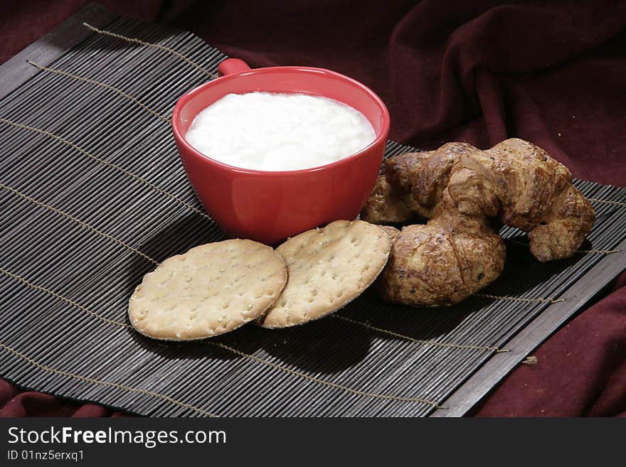 Yoghourt and croissants, biscuits isolated on dark background