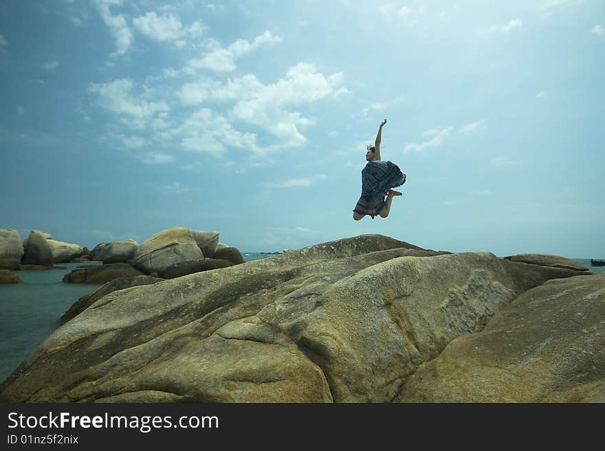 Jumping girl over stone beach background