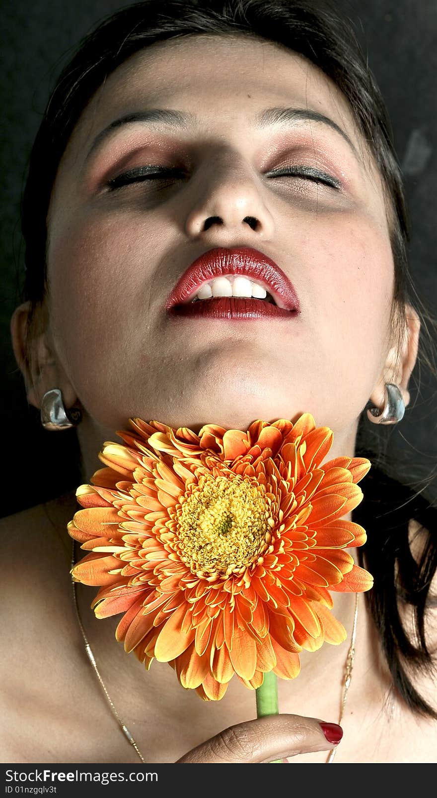 Girl with beautiful smile and orange flower looking beautiful. Girl with beautiful smile and orange flower looking beautiful