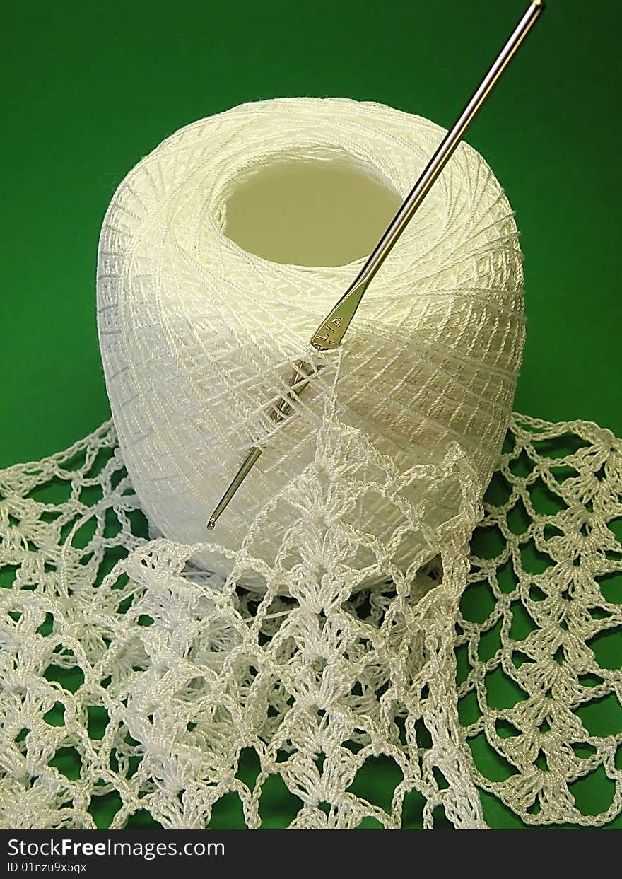 White crochet, bundle yarn and hook on the green background