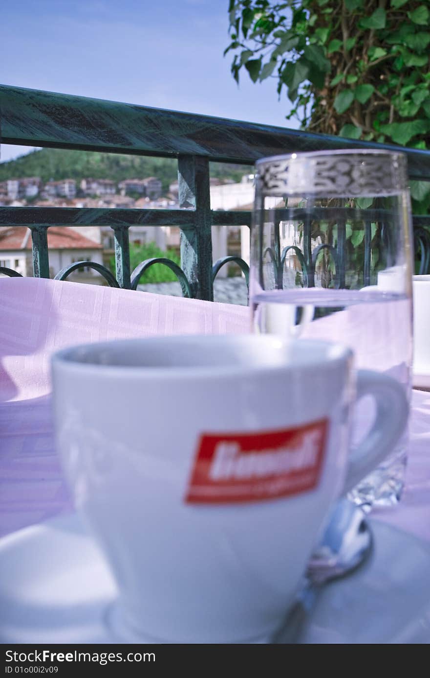 A cup of good black coffee with a glass of natural mineral water on a hotel terrace with a beautiful panorama to a small city in the mountains, shot in the spring of 2009. A cup of good black coffee with a glass of natural mineral water on a hotel terrace with a beautiful panorama to a small city in the mountains, shot in the spring of 2009