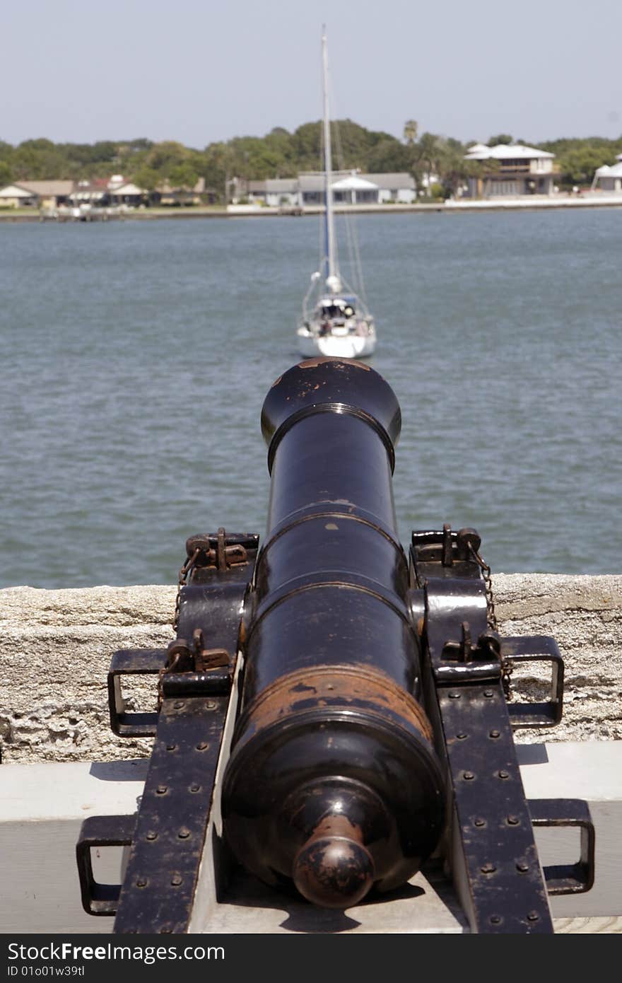 Old Spanish black powder cannon with a sailboat in the background . Old Spanish black powder cannon with a sailboat in the background .