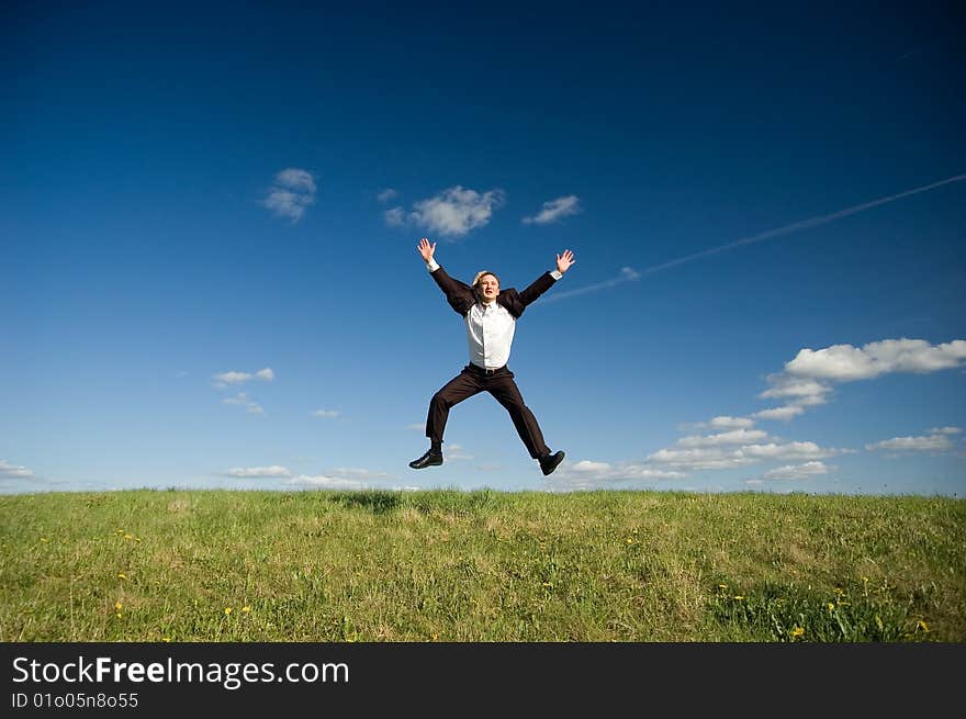 Jumping Businessman in meadow - green grass and blue sky. Jumping Businessman in meadow - green grass and blue sky