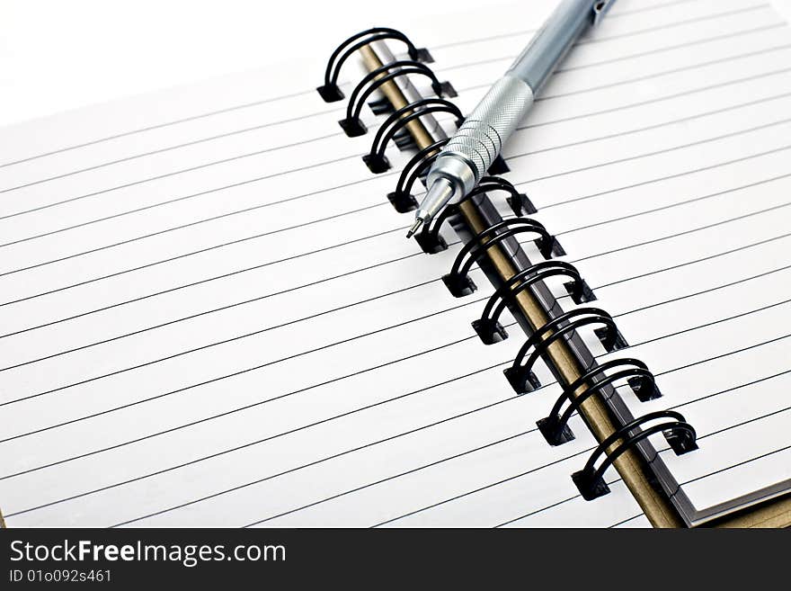 Pen made of metal resting on a blank notebook. Pen made of metal resting on a blank notebook.