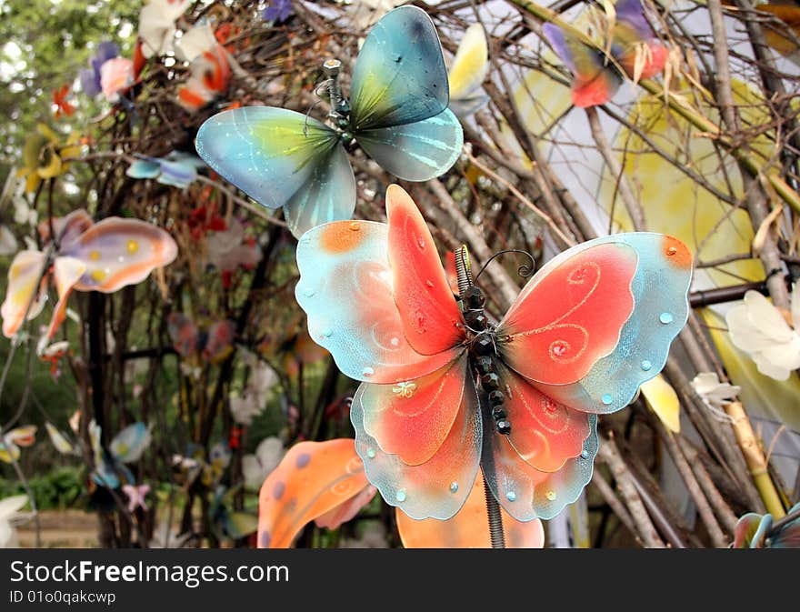 Some fake butterflies decorate an outdoor area in a garden. Some fake butterflies decorate an outdoor area in a garden.