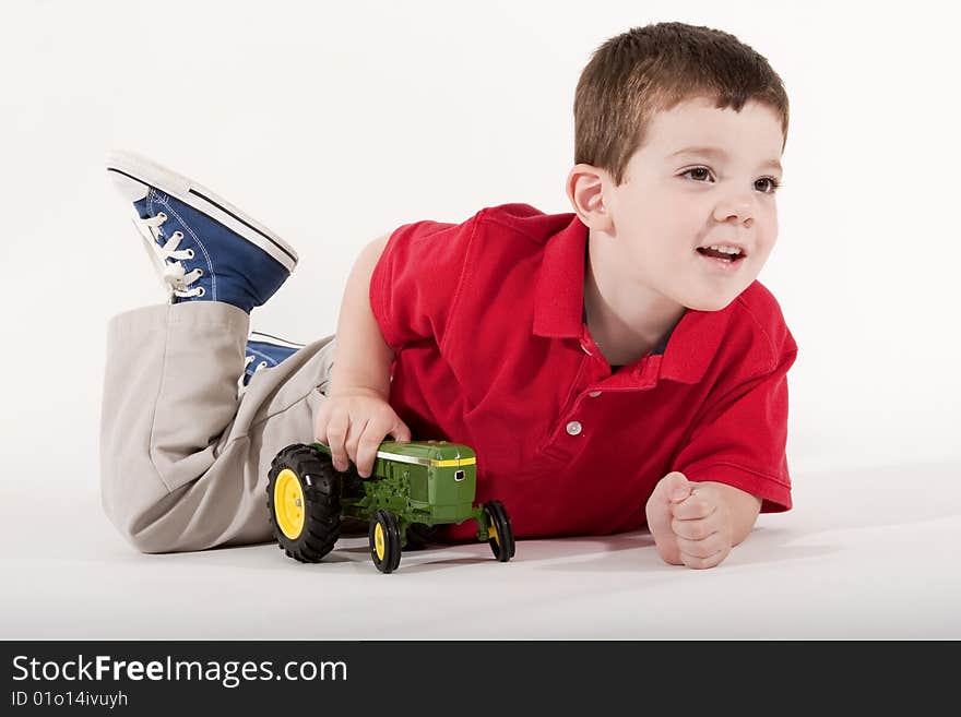 Young boy playing with a toy tractor on isolated background. Young boy playing with a toy tractor on isolated background