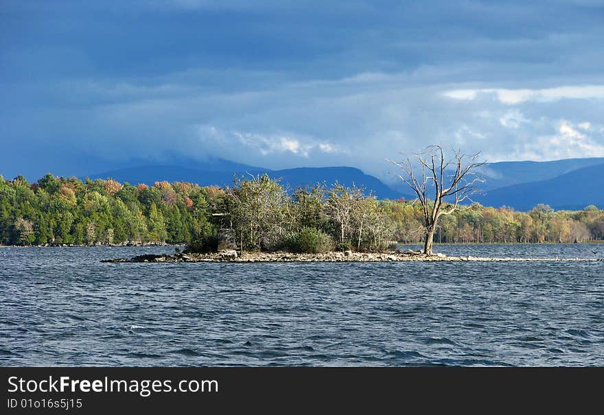 Small island in a lake with a storm in the distant mountains. Small island in a lake with a storm in the distant mountains