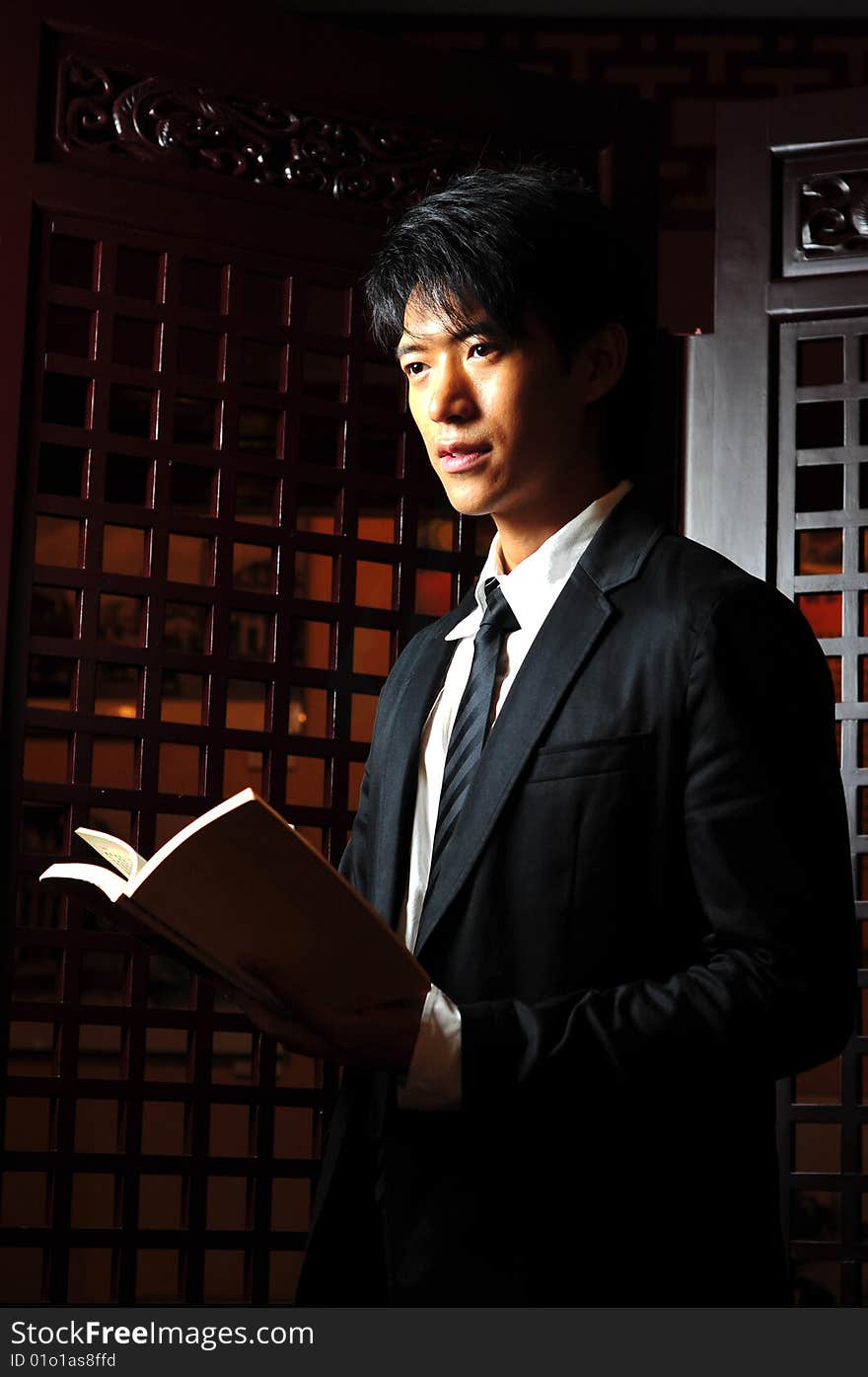 Asian man in business suit with book