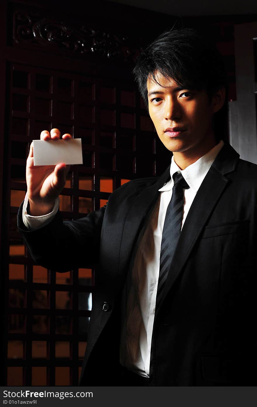 Asian man in business suit holding up a blank card. Asian man in business suit holding up a blank card