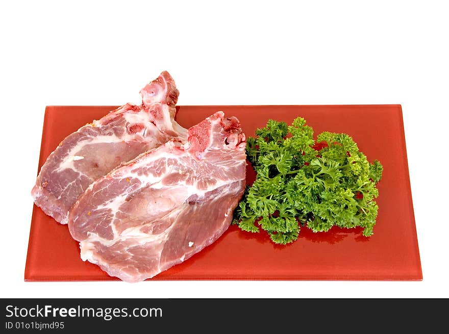 Pork chops on red plate, white background, studio shot